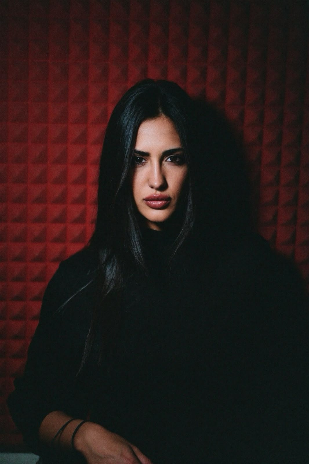Portrait of Lea Semic in front of a red acoustic wall, looking toward the camera